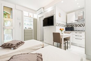 A modern hotel room with a bed, a desk, a chair, a TV, and a kitchenette. - GuestHost - The apartment is located on the ground floor of a building.It does not have an elevator but there is a step to access.Accommodates two people with two single beds.20 square meters of space overlooking the internal garden of the building.We ar (Bologna)