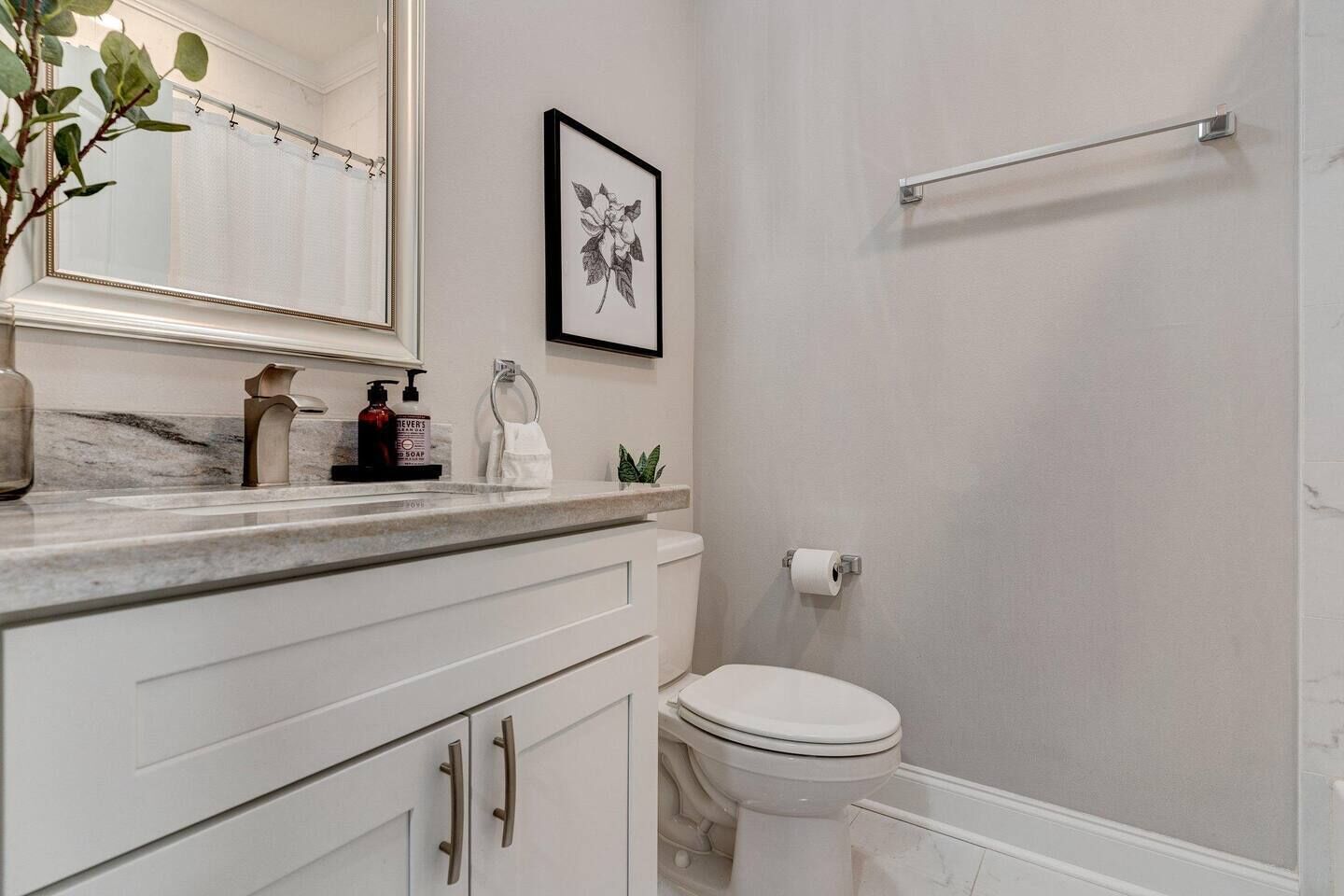 A bathroom with a toilet, sink, and mirror.