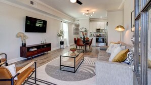 A modern living room with a TV, sofa, coffee table, and dining area.