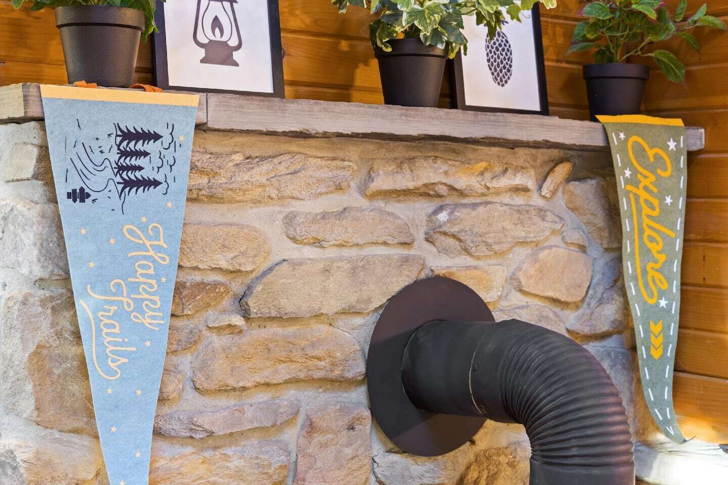 Una chimenea de piedra con dos banderines, uno que dice "Happy Trails" y el otro "Breathe".