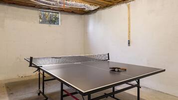 Un tavolo da ping pong in una stanza con pavimento in cemento e soffitto in legno.
