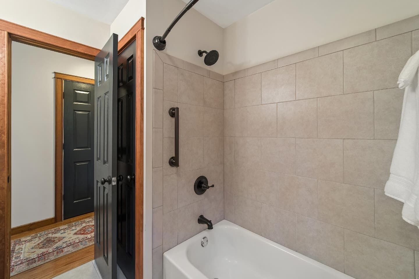 A bathroom with a bathtub, a shower, and a door leading to another room.