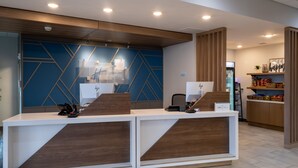 A reception desk with a modern design, featuring a blue geometric wall and wooden accents.