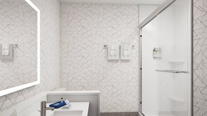 A modern bathroom with a geometric patterned wall, a white sink with a chrome faucet, and a glass shower enclosure.