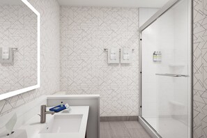 A modern bathroom with a geometric patterned wall, a white sink with a chrome faucet, and a glass shower enclosure.
