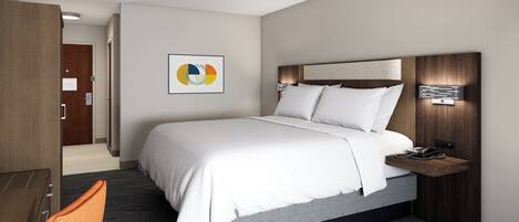 A hotel room with a large bed, a bedside table with a phone, and a wall-mounted artwork.