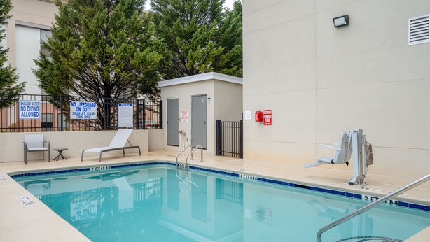 A swimming pool with safety signs, a lifeguard station, and lounge chairs.