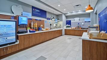A modern breakfast area with a digital menu board, various food stations including yogurt, cereal, and fruit, and a bakery section.