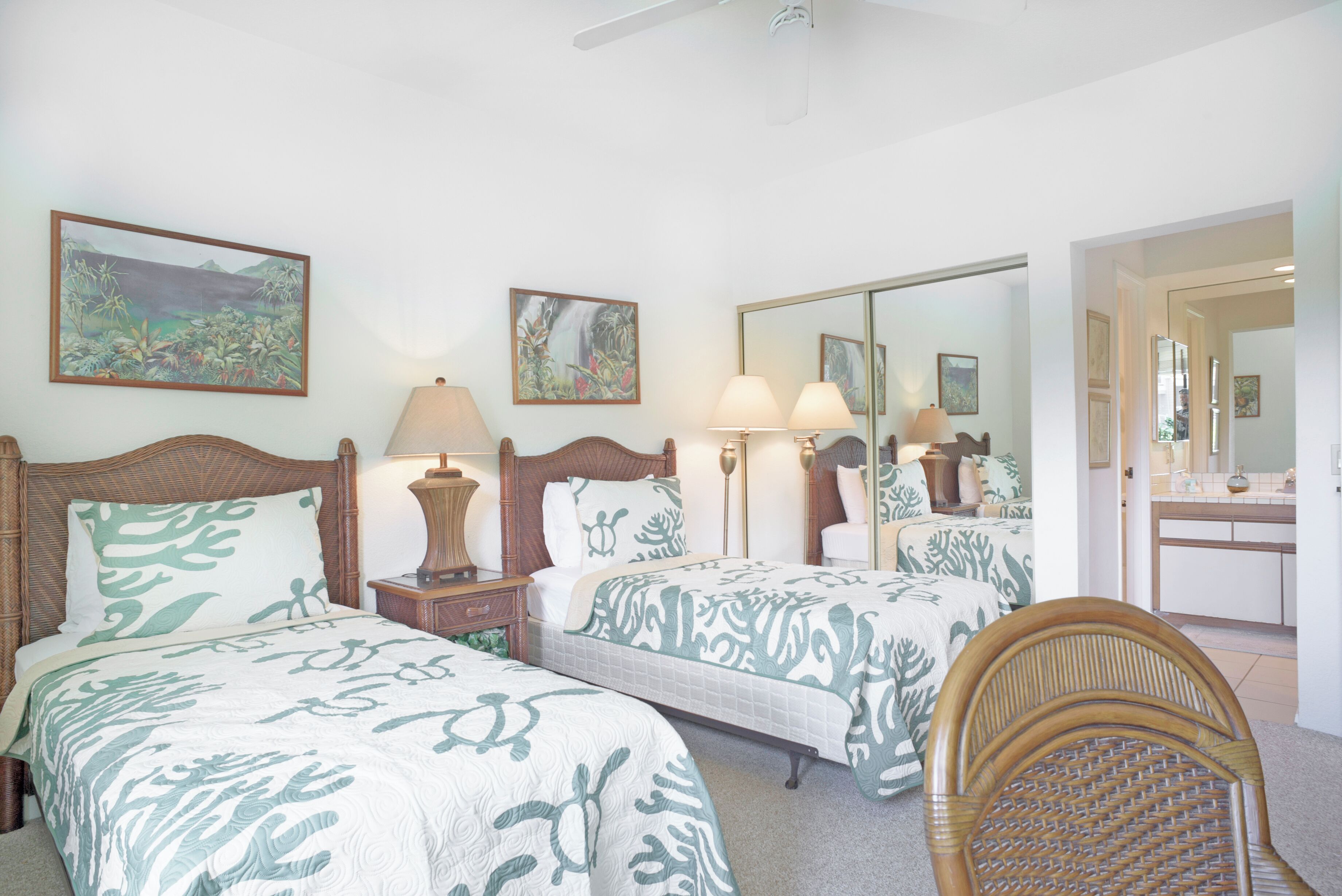 A hotel room with two beds, a large mirror, a wooden chair, and artwork on the walls.