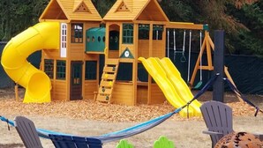 Une cabane en bois avec un toboggan jaune et une échelle d’escalade.