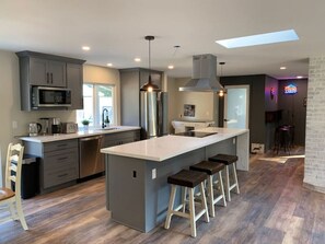 Une cuisine moderne avec des meubles gris, des appareils en acier inoxydable et un îlot central doté de tabourets.