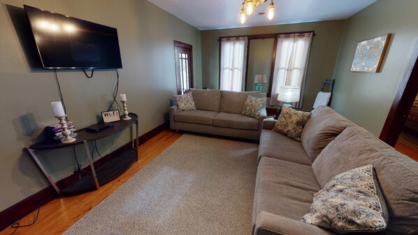 A living room with a flat-screen TV, a sofa, a coffee table, and a rug.