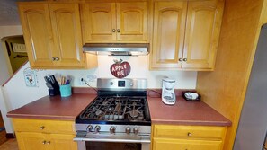 A kitchen with wooden cabinets, a gas stove, and a coffee maker.