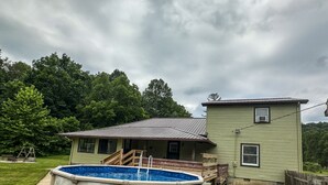 A house with a swimming pool, a covered porch, and a fenced yard.