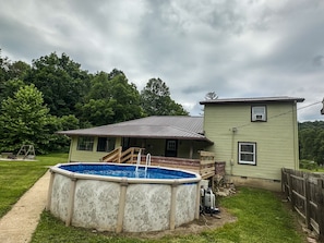 Une maison avec une piscine, une véranda et une cour clôturée.