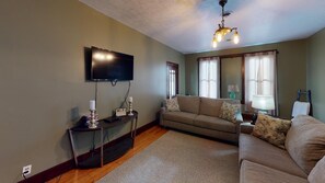 Ein Wohnzimmer mit Flachbildfernseher, einer Couch, einem Couchtisch und einem Teppich.