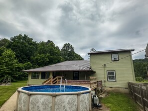Uma casa com piscina, um deck coberto e uma garagem separada.