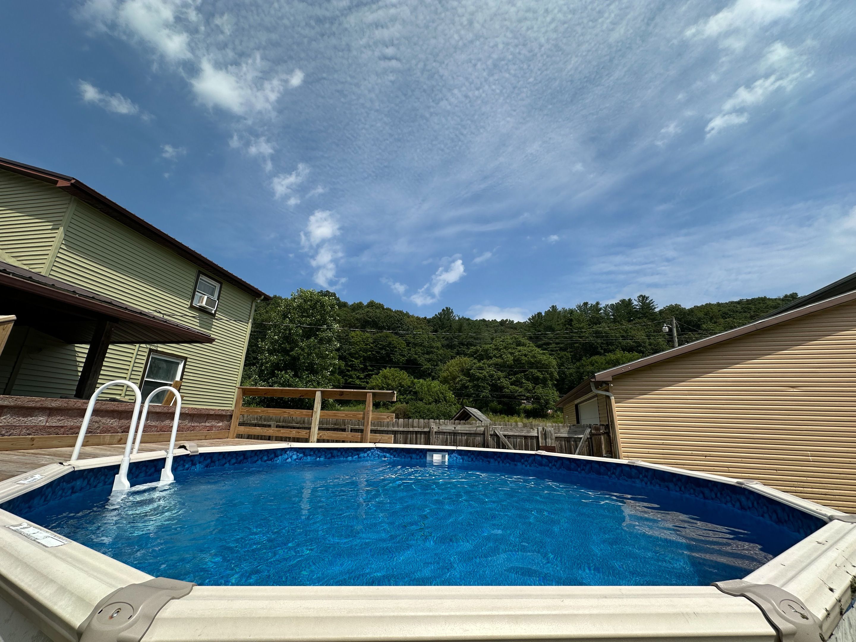 A swimming pool with a wooden deck and a metal ladder.