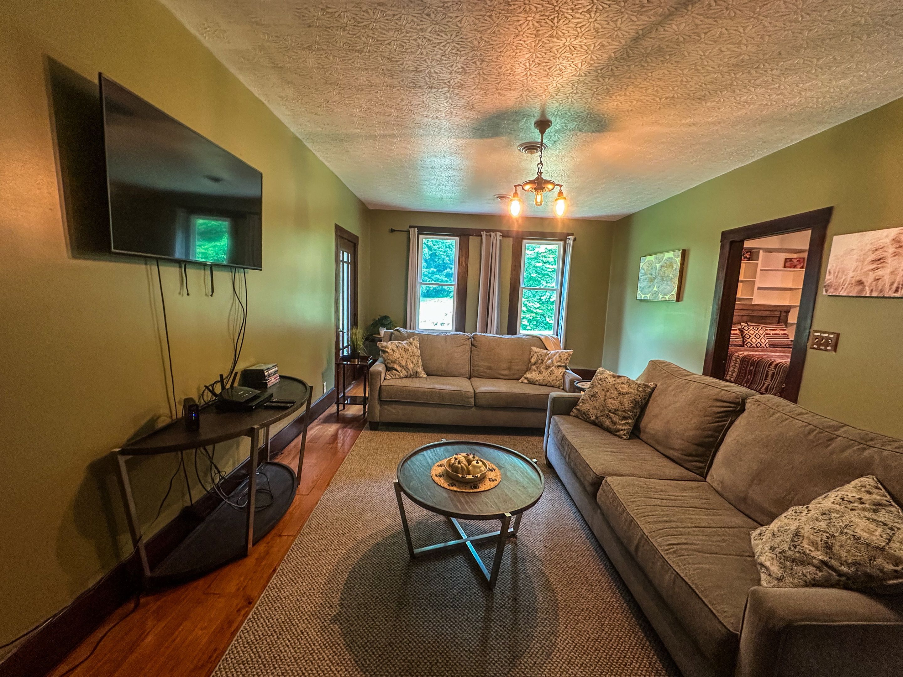 A living room with a sofa, a coffee table, a TV, and a ceiling fan.