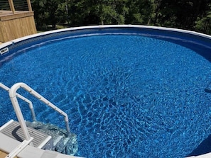 Une piscine d’un bleu éclatant, dotée d’une terrasse en bois et d’une échelle en métal.