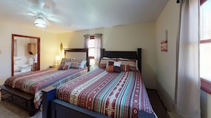 Une chambre double avec deux lits, un ventilateur de plafond, une fenêtre avec des rideaux et une salle de bain avec des toilettes et un lavabo.
