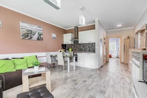 A modern kitchen with white cabinets, a marble backsplash, and a dining area with a table and chairs.