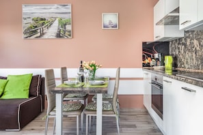A modern kitchen with white cabinets, a marble countertop, and a dining area with a table set for four.