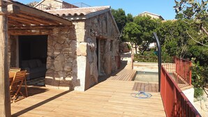 Un bâtiment en pierre doté d’une terrasse en bois et d’un espace piscine.