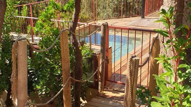 Une terrasse en bois qui mène à une piscine, avec vue sur les montagnes.