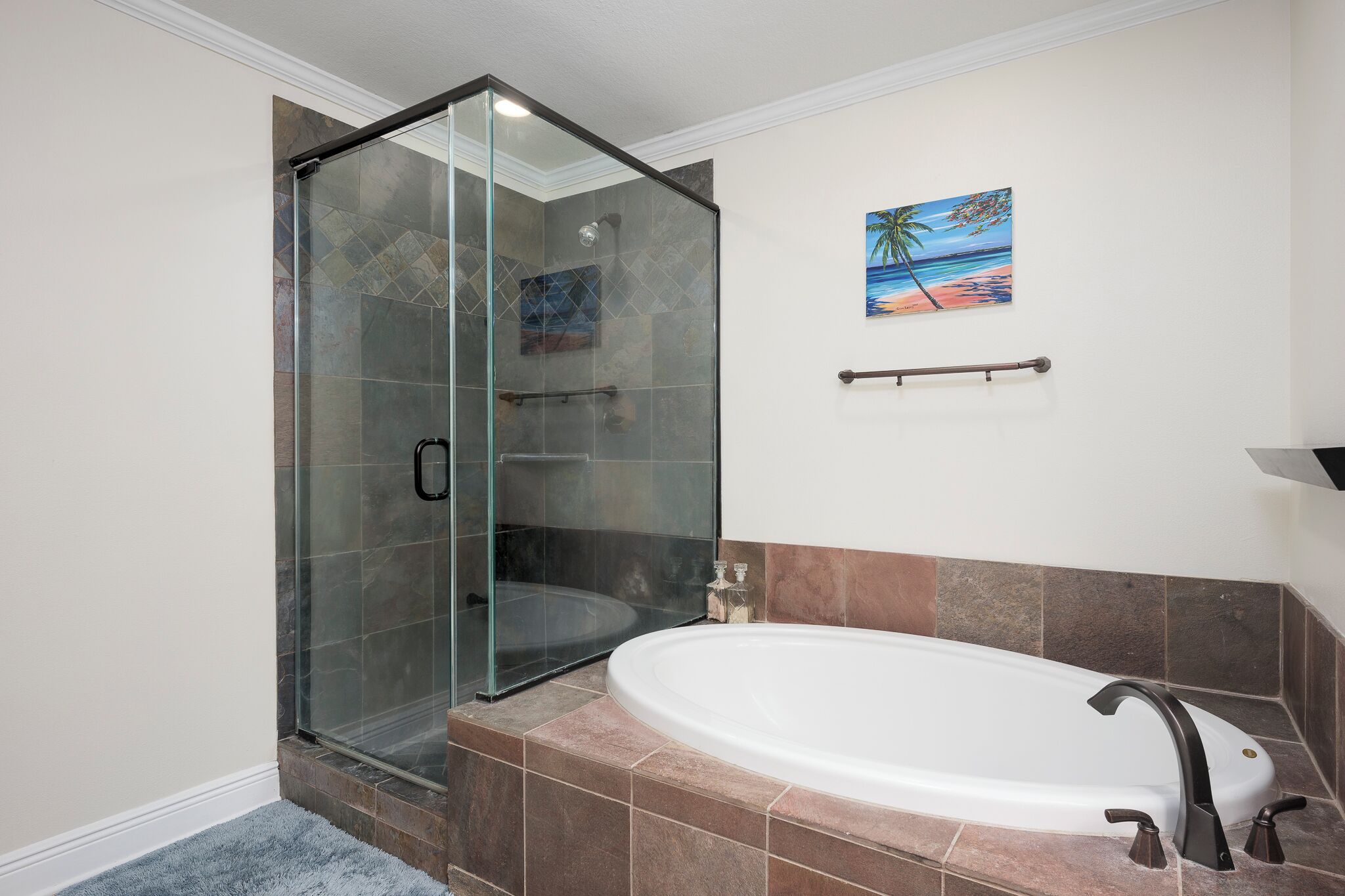 Une salle de bain moderne dotée d’une douche à parois de verre, d’une baignoire sur pieds et d’un tableau sur le thème de la plage.