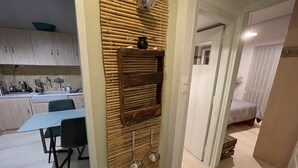 A modern kitchen with wooden cabinets, a dining table with chairs, and a bamboo wall panel. - Enjoy Chania (Chania)