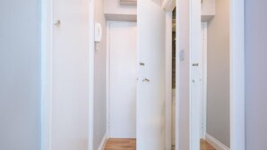 A narrow hallway with white walls and wooden flooring.