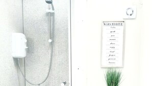 A modern bathroom with a glass-enclosed shower, a white toilet, and a wall-mounted sign listing ways to love. - Swansea Beach Townhouse (Swansea)