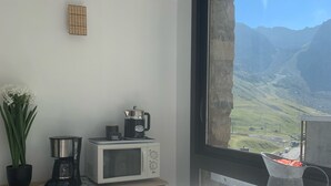 A small kitchen with a coffee maker, microwave, and a view of a mountainous landscape through a window.