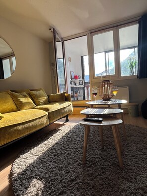 A living room with a sofa, a coffee table, and a view through a large window.