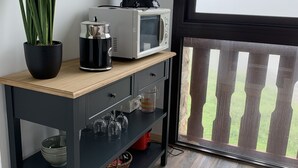 A small kitchen area with a microwave, coffee maker, and potted plant.