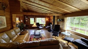 A cozy cabin interior with a leather sofa, a coffee table, and a TV in the center. - Holiday home Kappeled (Smålandsstenar)