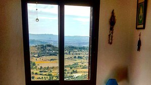 A bedroom with a large window offering a view of a rural landscape. - Casinha Dentro do Centro Historico Vista Deslumbrante (Belmonte)
