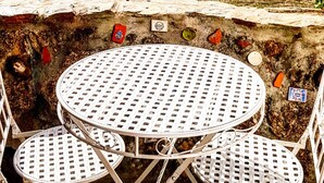 A stone wall with a round table and two chairs, overlooking a rural landscape with fields and scattered houses. - Casinha Dentro do Centro Historico Vista Deslumbrante (Belmonte)