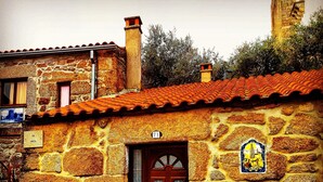 A stone building with a red-tiled roof, a wooden door, and a small window. - Casinha Dentro do Centro Historico Vista Deslumbrante (Belmonte)