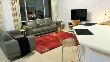 Relax in this stylish living room with a sofa, dining table, and flat-screen TV.