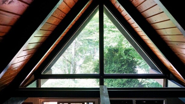 Una ventana triangular con vistas a un bosque.