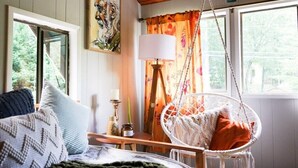 Una habitación con una cama, una silla colgante, una lámpara y un cuadro en la pared.