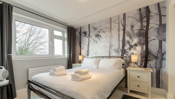 A bedroom with a bed, two bedside tables with lamps, a window, and a wall mural. - Stunning Clifton Flat in Amazing Central Location (Bristol)