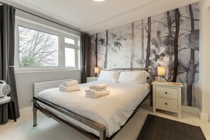 A bedroom with a bed, two bedside tables with lamps, a window, and a wall mural. - Stunning Clifton Flat in Amazing Central Location (Bristol)
