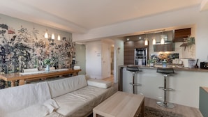 A modern living room with a sofa, a wooden coffee table, and a kitchen area with a bar stool. - Stunning Clifton Flat in Amazing Central Location (Bristol)