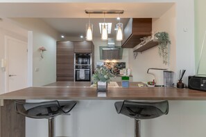 A modern kitchen with a central island, bar stools, a built-in oven, and pendant lighting.