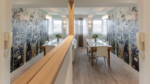 A modern dining area with a long wooden bench, two tables with chairs, and cityscape murals on the walls. - Stunning Clifton Flat in Amazing Central Location (Bristol)