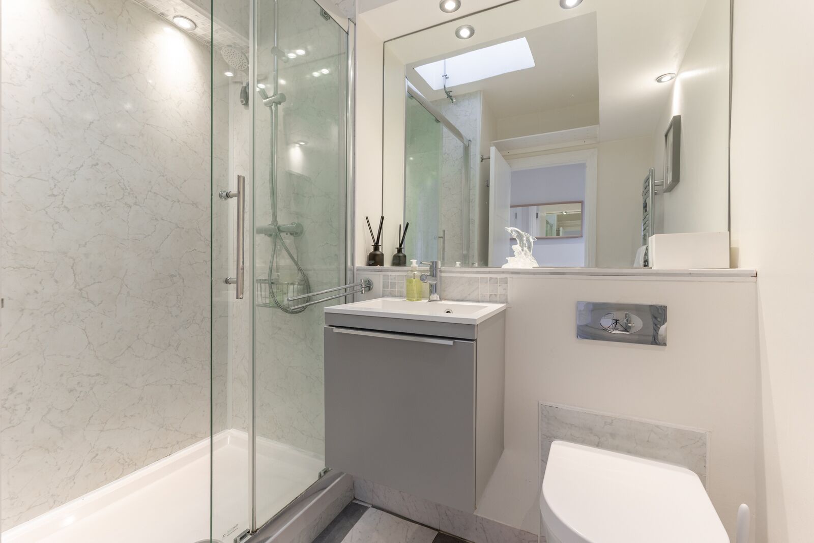 A modern bathroom with a glass-enclosed shower, a sink with a mirror above, and a toilet.