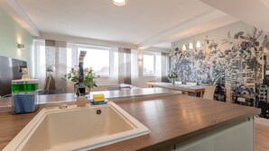 A modern kitchen with a large island, built-in appliances, and a cityscape mural. - Stunning Clifton Flat in Amazing Central Location (Bristol)